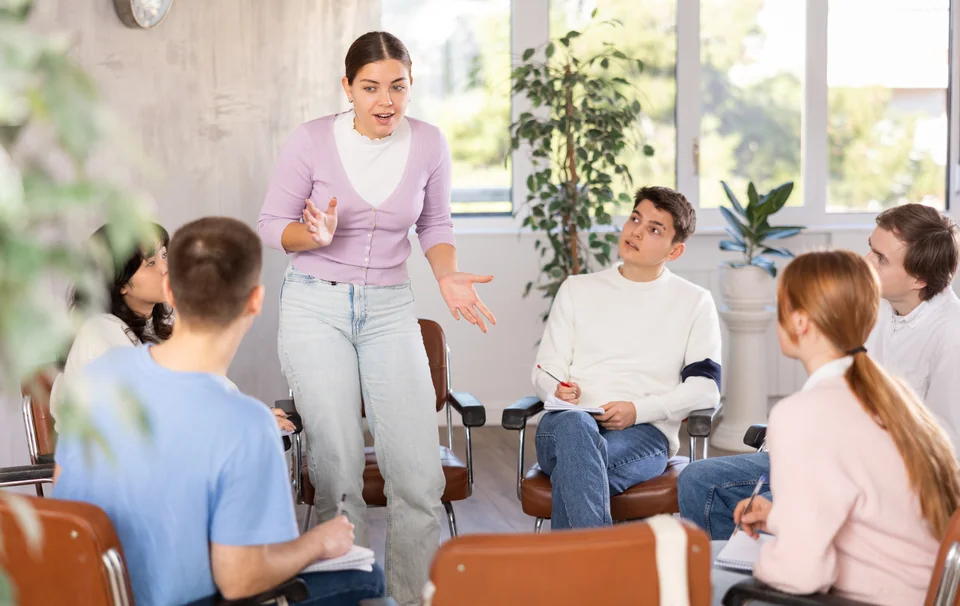 Adult learners practising discussion in a small group, with one participant speaking
