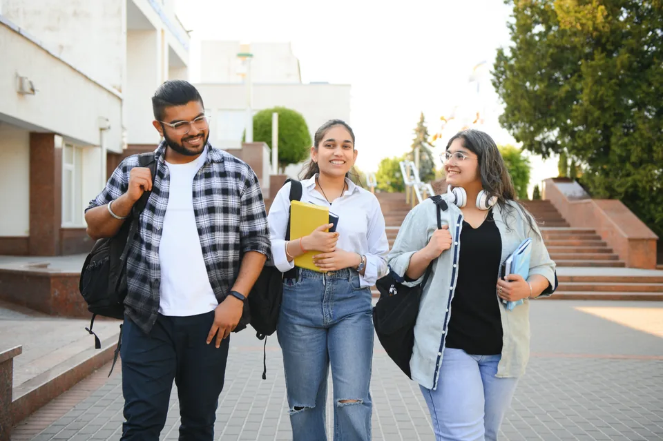 Three students walking together outdoors with notebooks and backpacks